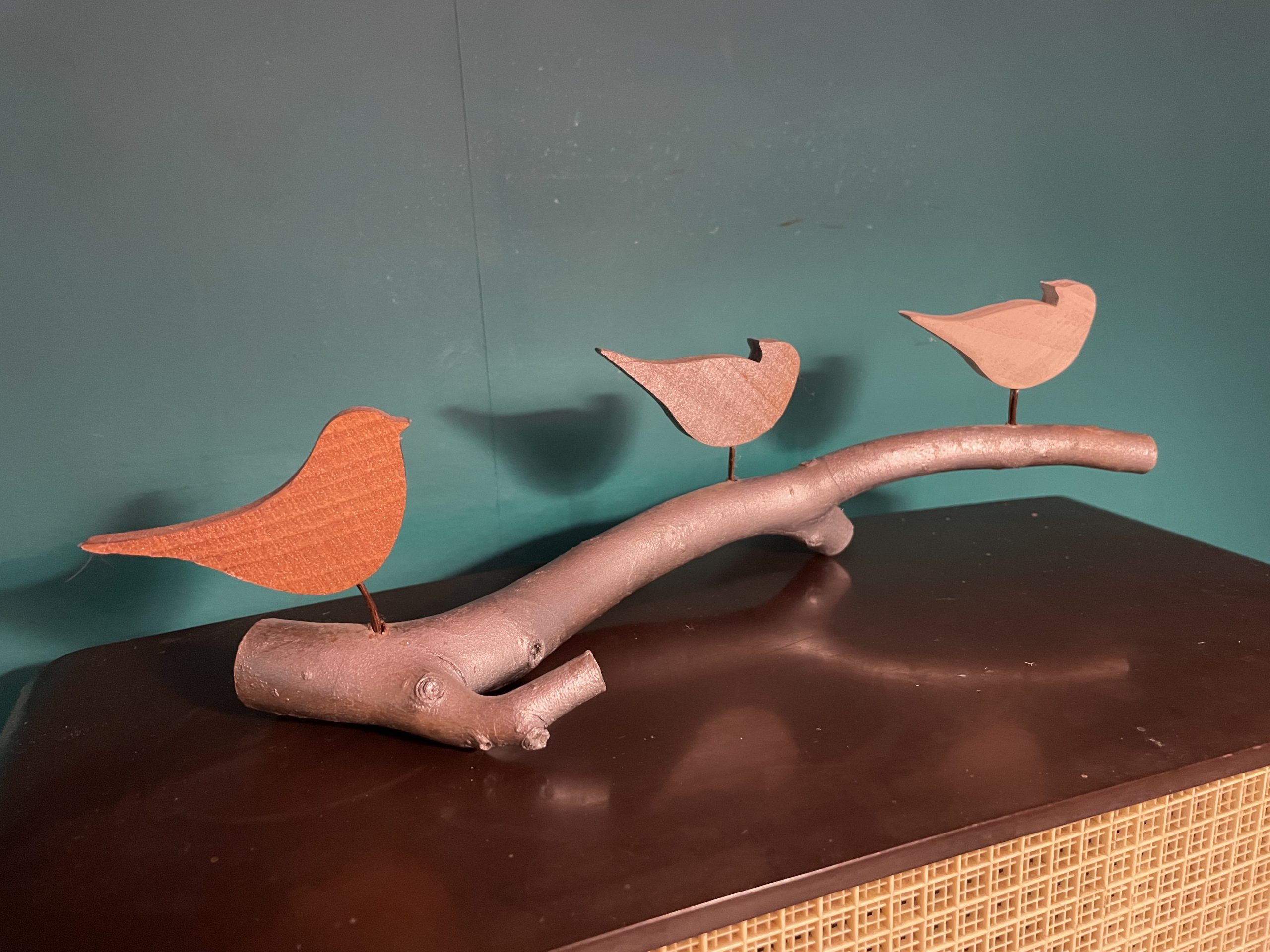 Handcrafted bird sculpture with three painted wooden birds on a silver-painted branch, made from reclaimed wood with copper wire legs. From the front 2